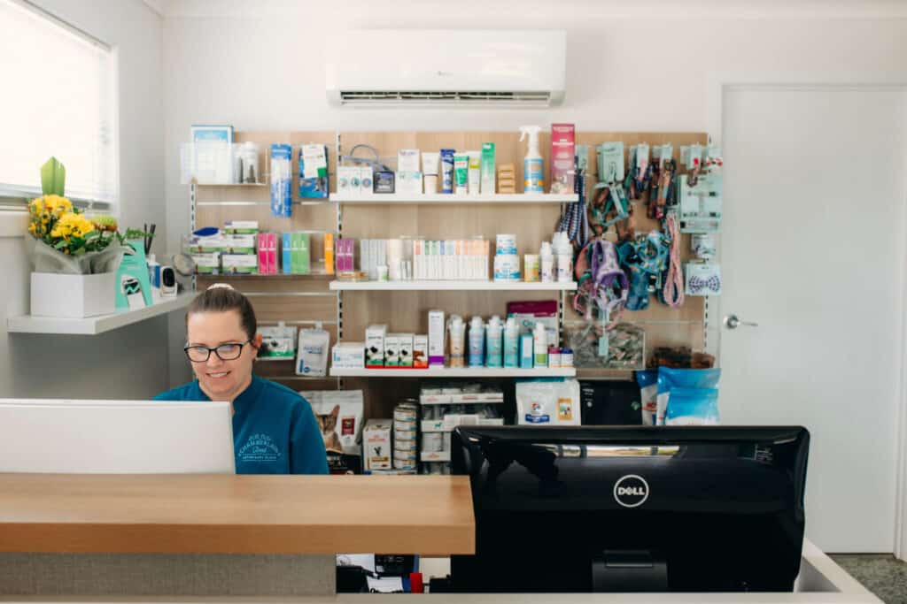 A woman sitting at a desk assisting customers with their medical needs at Chamberlein Road Veterinary Clinic